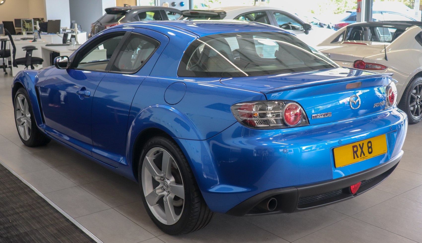 Blue sporty coupe rear side with alloy wheels and distinct taillights.