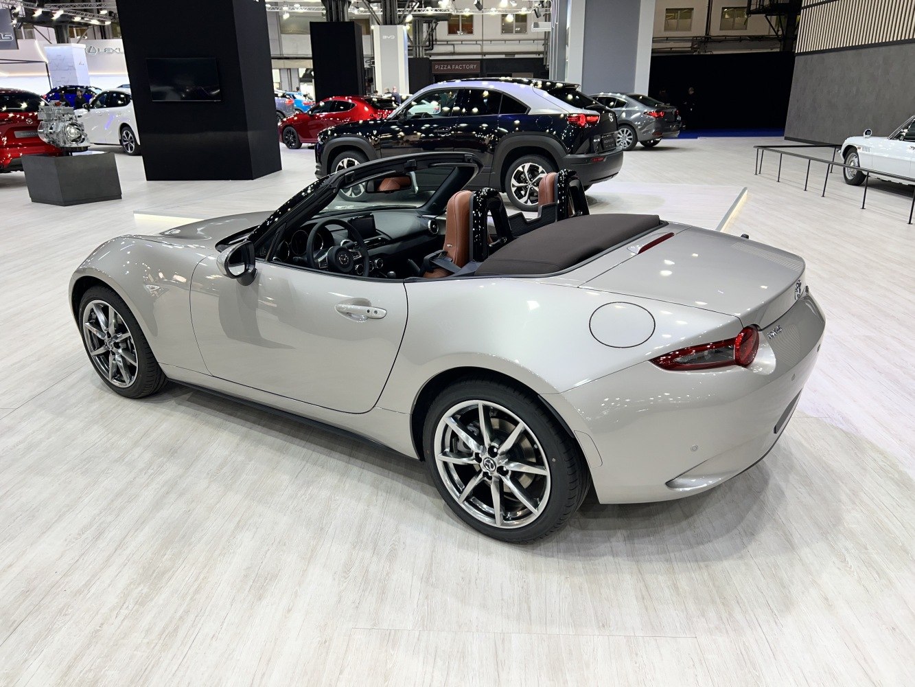 Convertible roadster rear side with alloy wheels and brown leather seats.