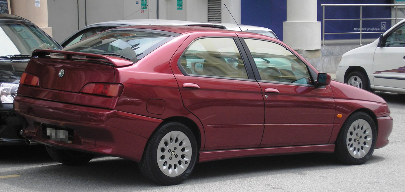 Rear-side view of red hatchback with spoiler and alloy wheels