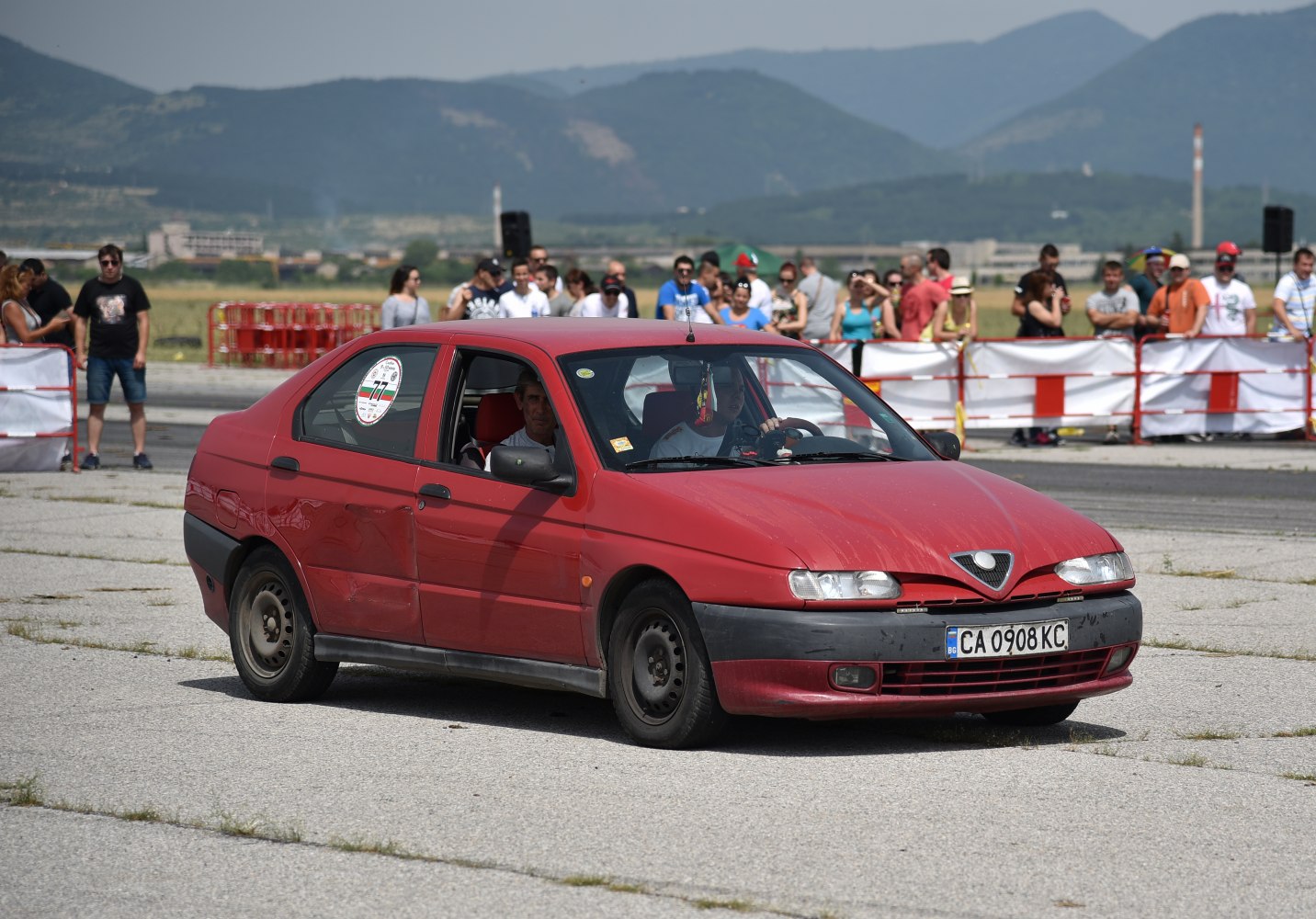 Red sedan with distinctive front grille and worn black bumper