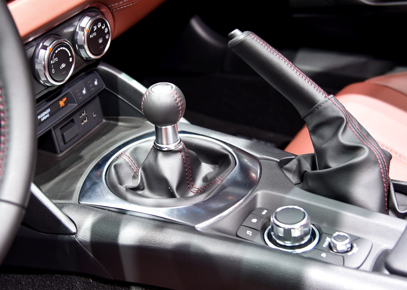 Manual gearshift and center console with control knobs and handbrake in leather stitching