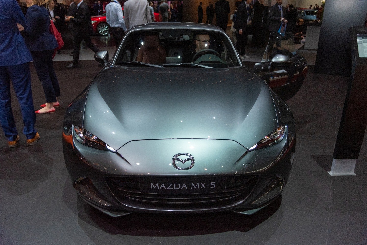 Front view of sleek sports coupe with open driver door and aerodynamic hood