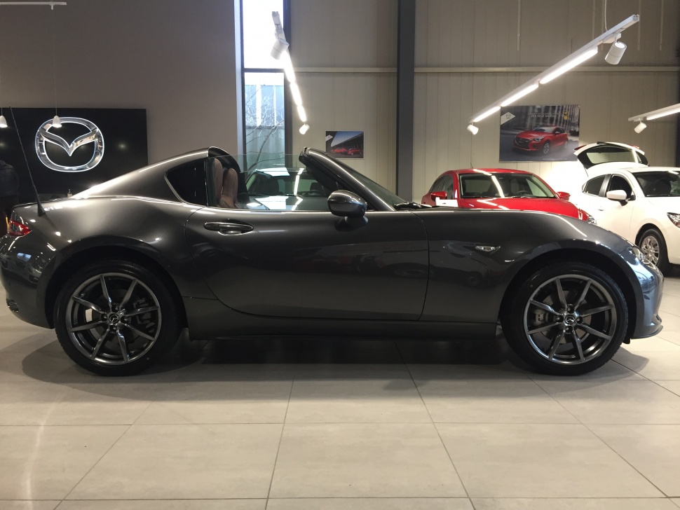 Side profile of a sleek gray convertible with hardtop roof and alloy wheels.