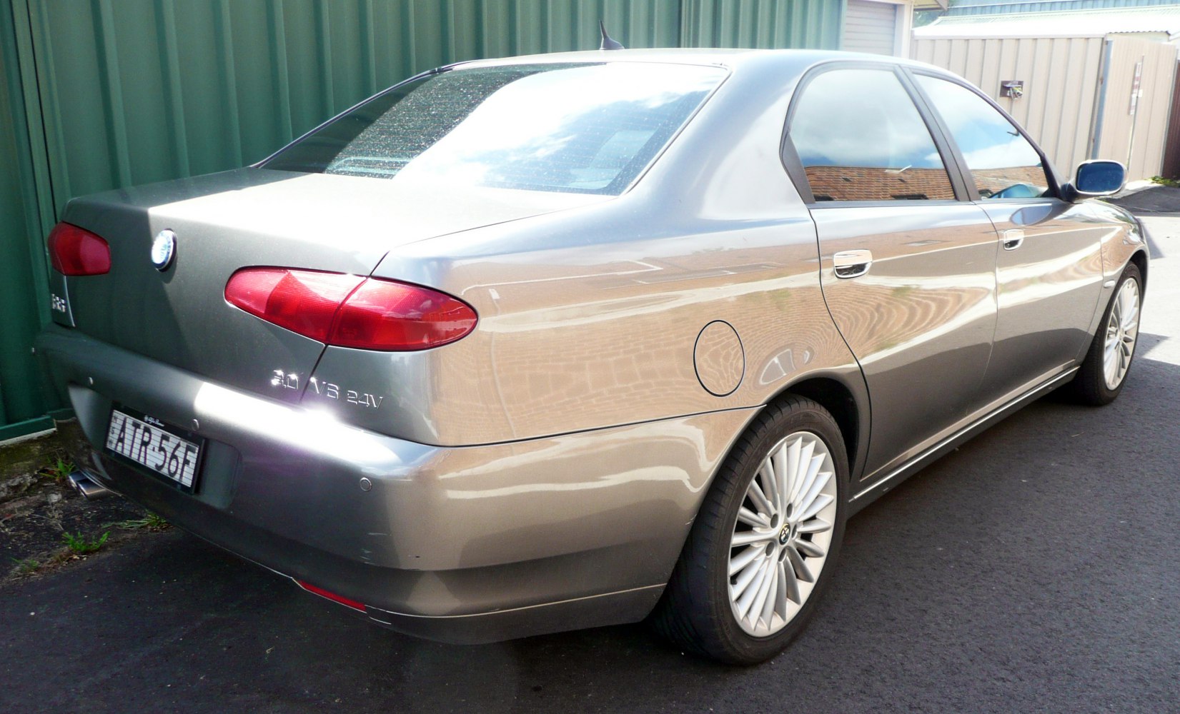 Rear three-quarter luxury sedan with red tail lights and multi-spoke alloy wheels