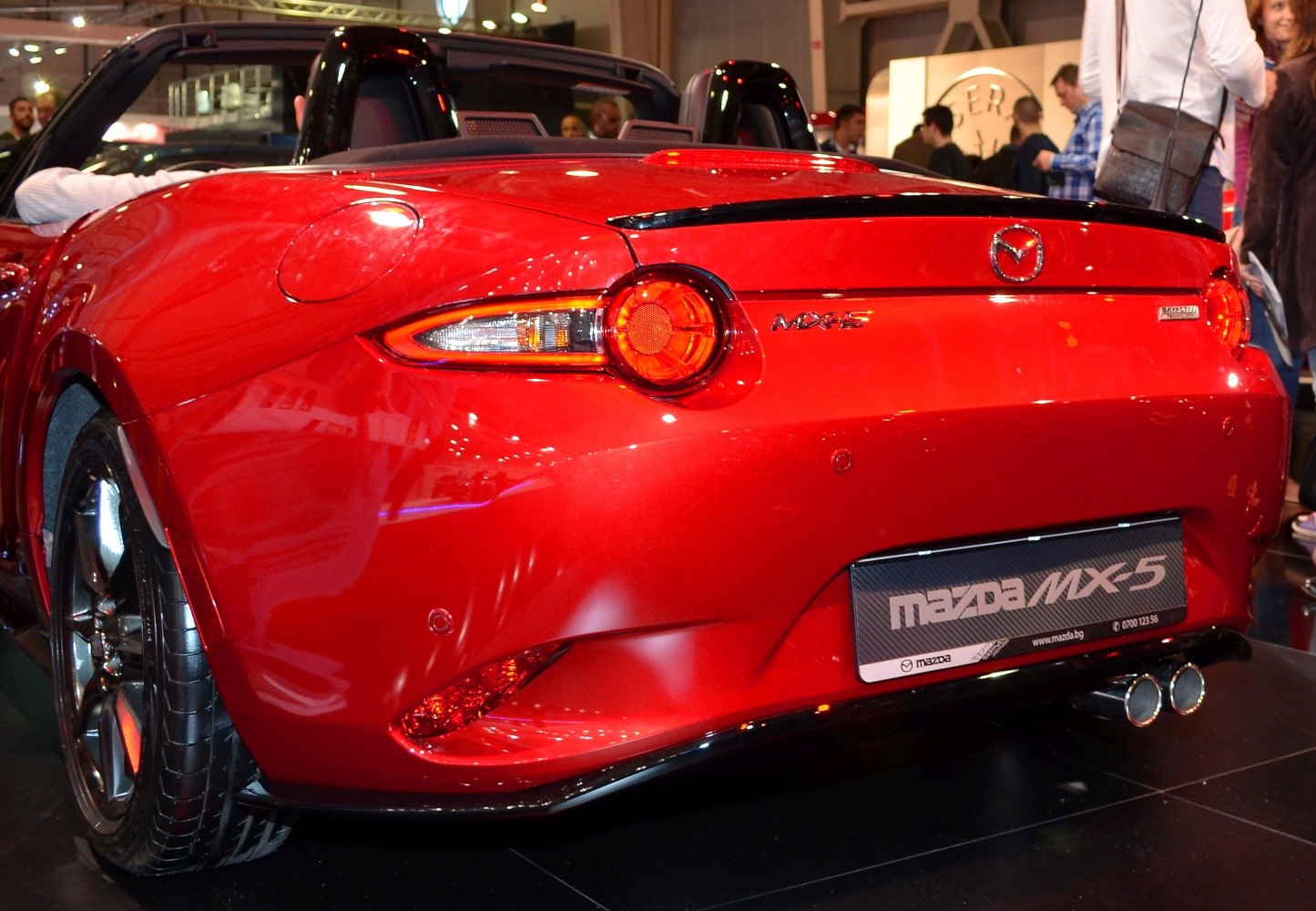 Red convertible rear with distinct round tail lights and dual exhaust pipes