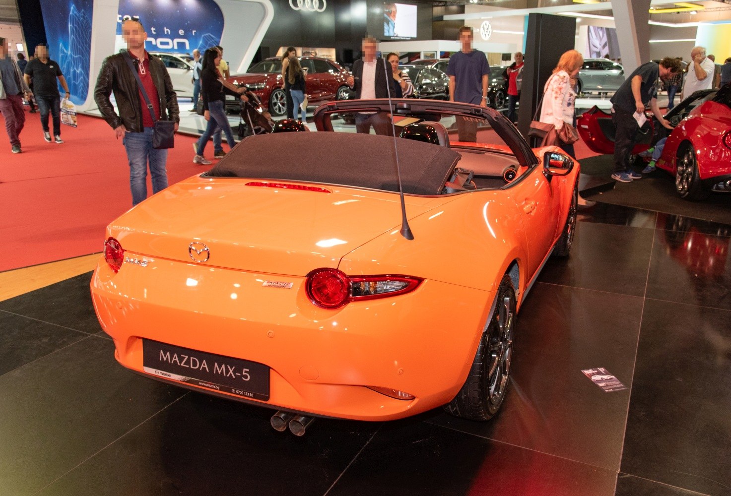 Rear view of an orange convertible with round taillights and dual exhaust