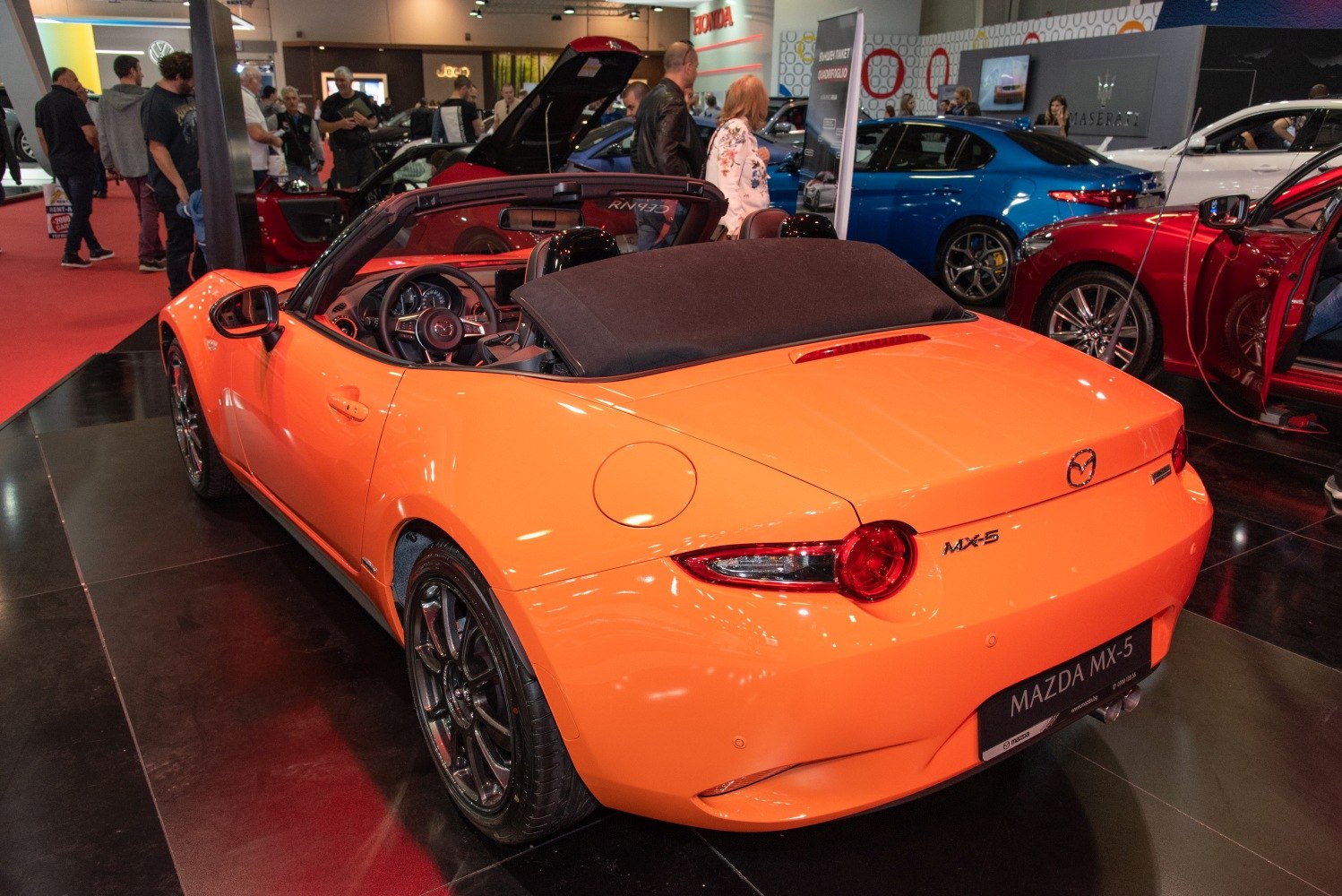 Orange convertible roadster with folded soft top and round rear lights
