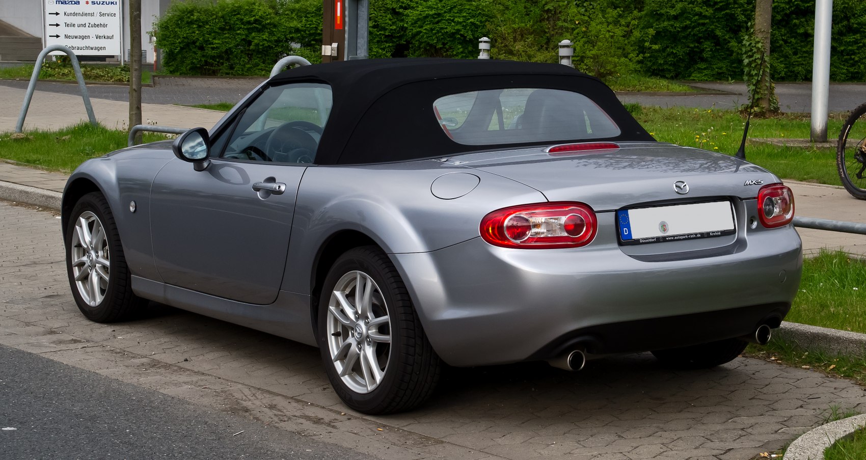 Rear and side view of silver convertible with soft-top roof and alloy wheels