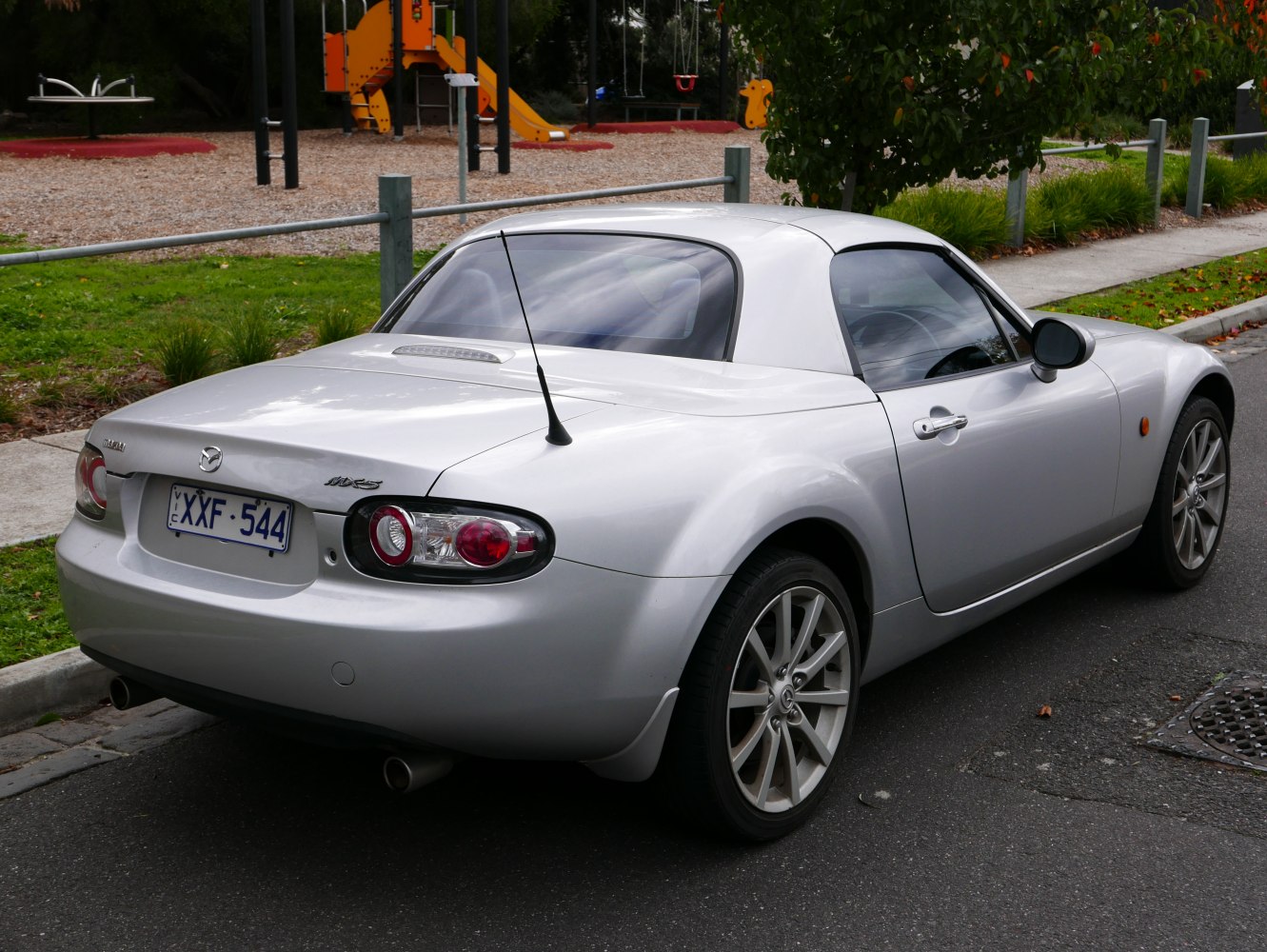 Rear view of silver coupe with hardtop featuring taillights and alloy wheels
