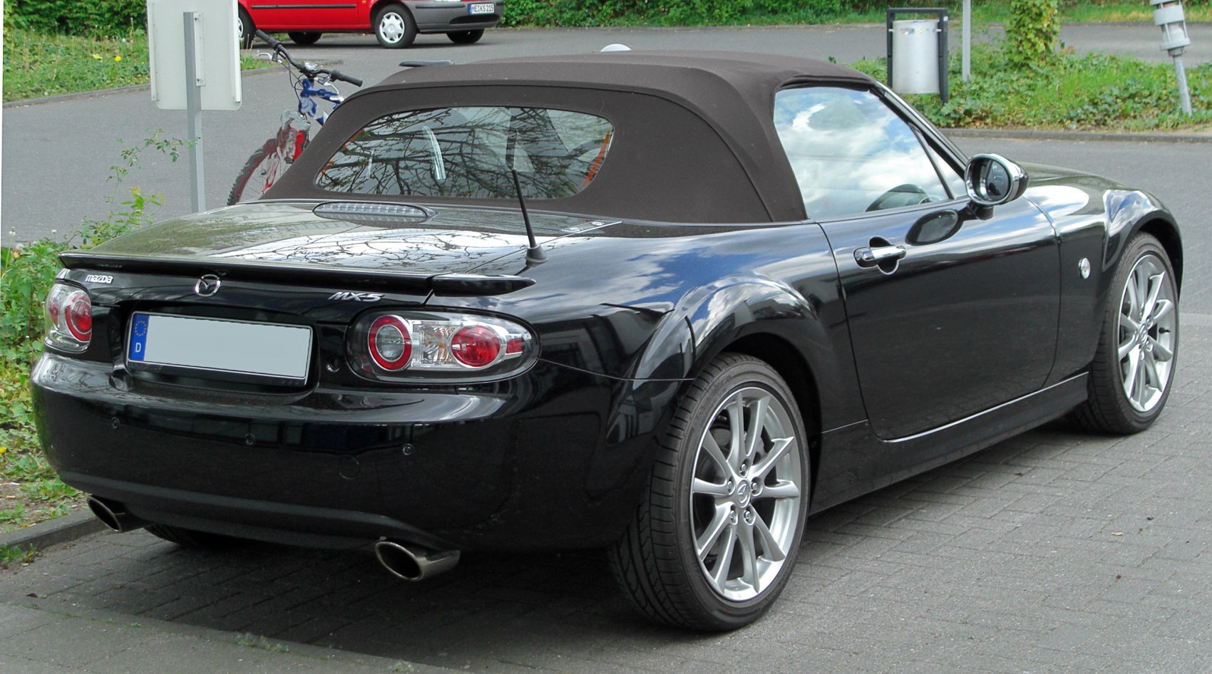 Rear view of a black convertible with soft top and dual exhaust