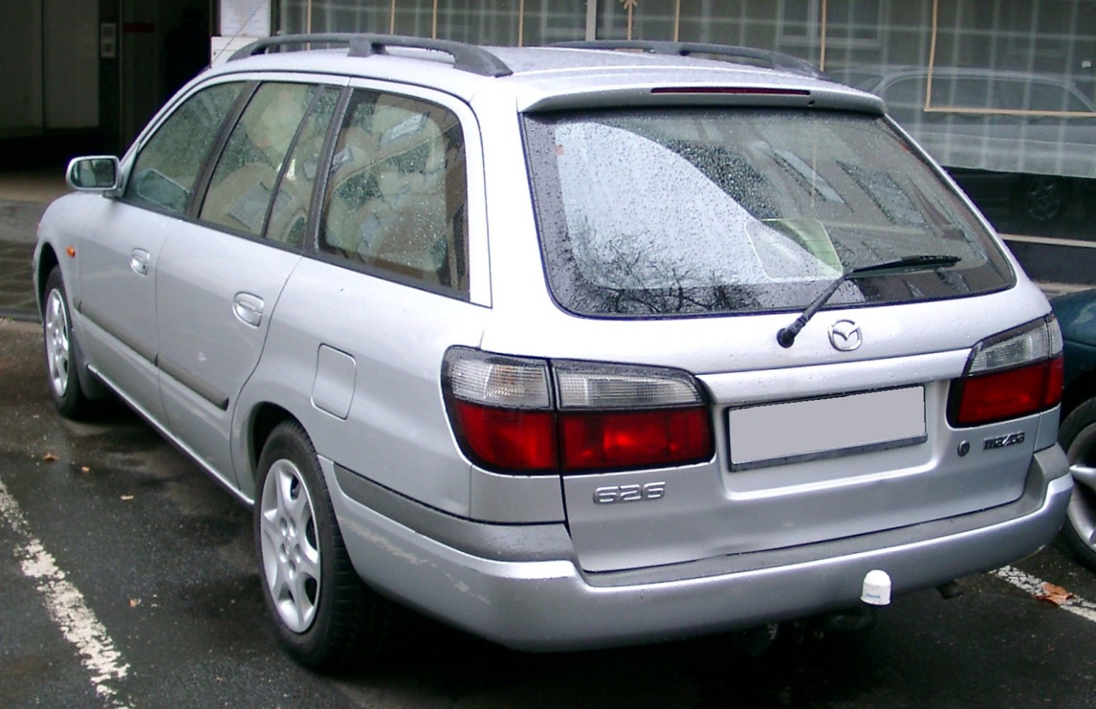 Rear view of a silver station wagon with tail lights and rear windshield wiper