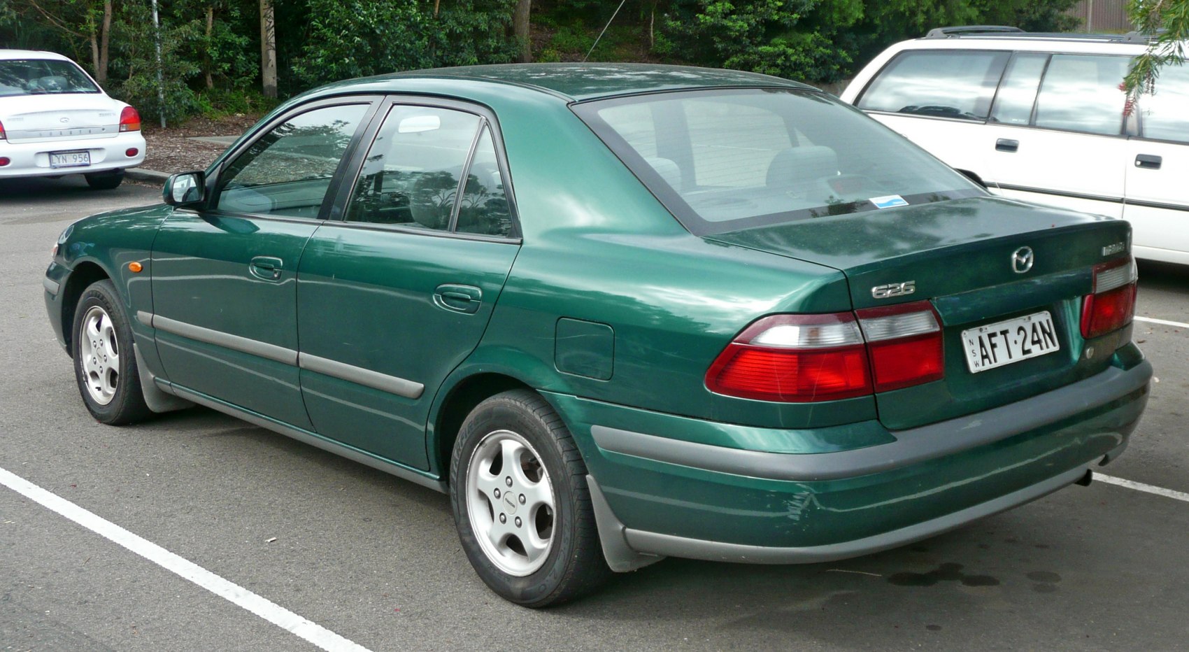 Rear and side view of a green sedan with distinct taillights and alloy wheels