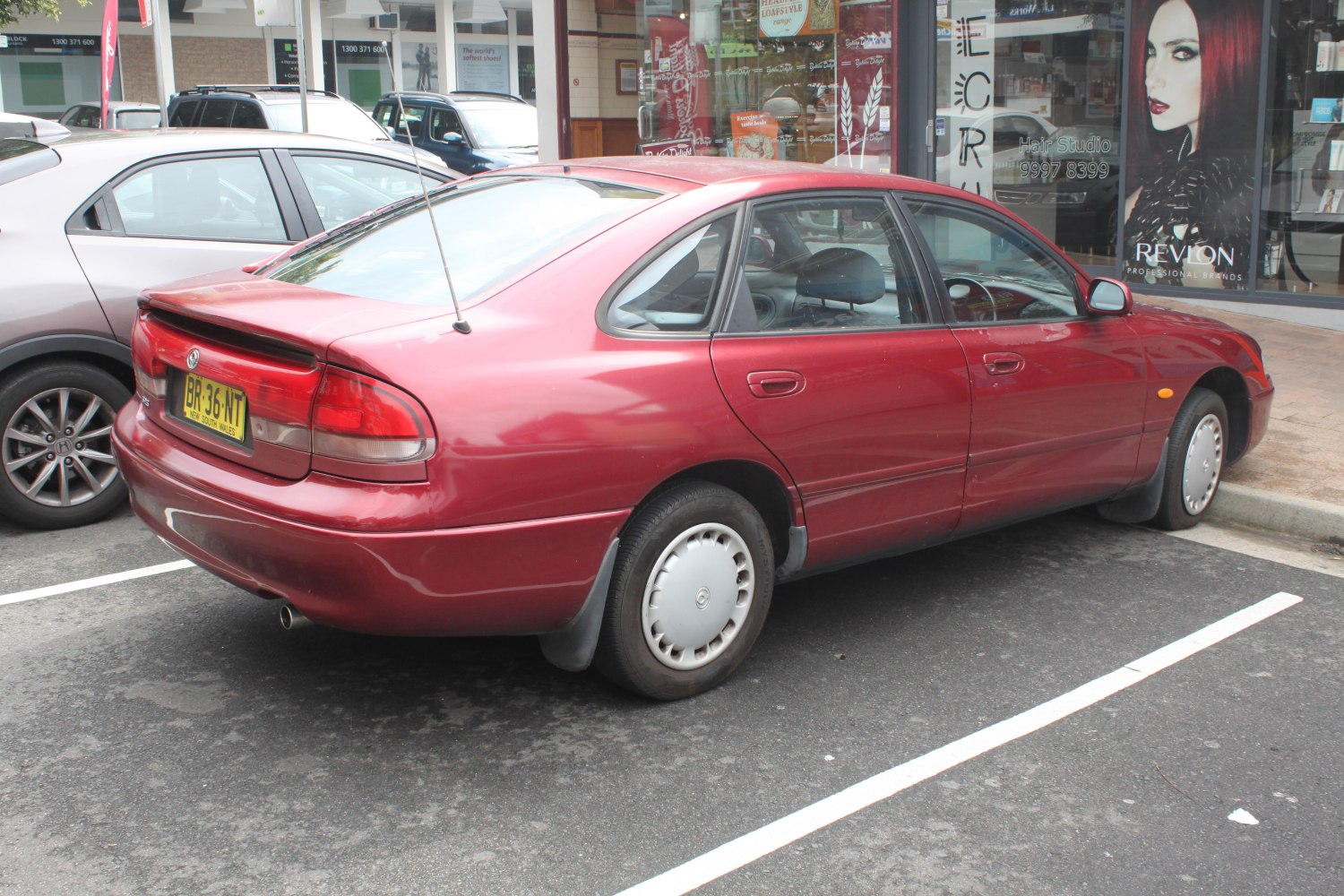 Four-door sedan with rear spoiler and rounded taillights from rear-side angle