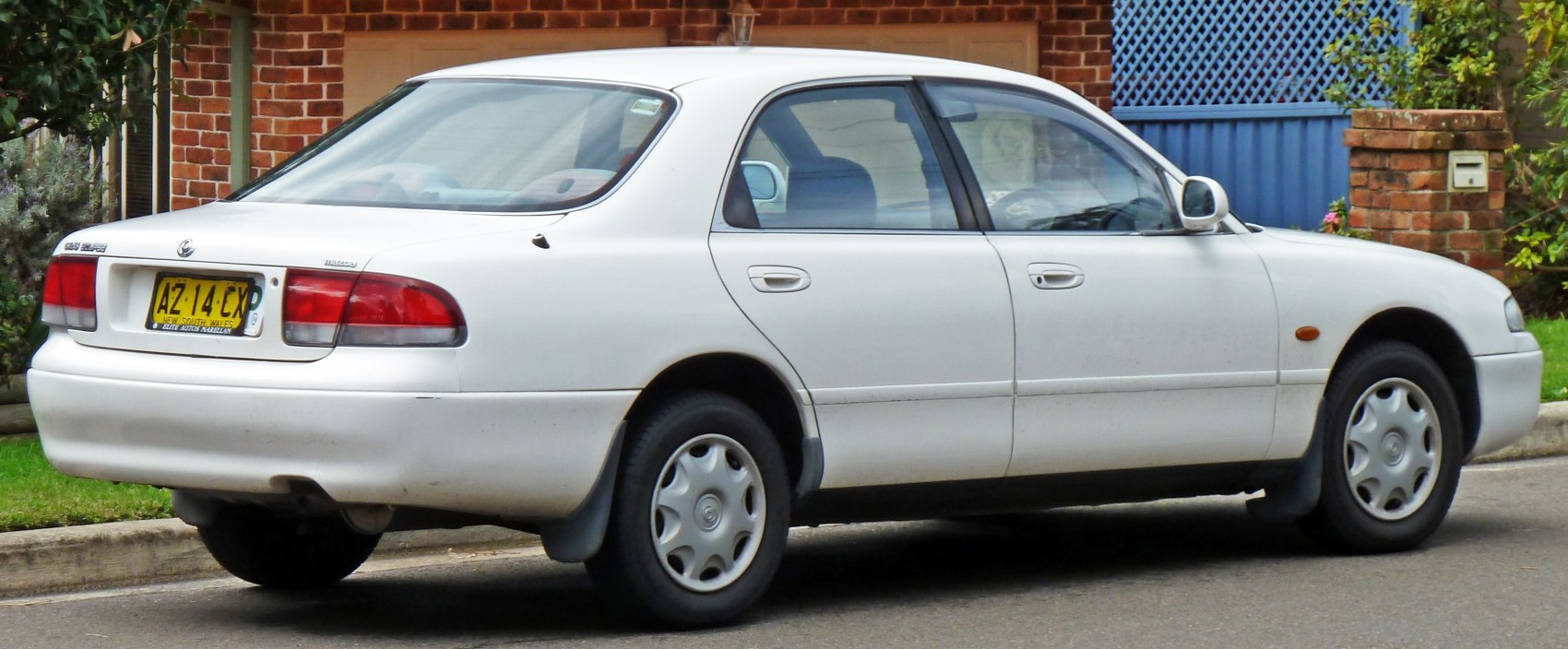 Rear side view of white sedan with hubcap wheels.