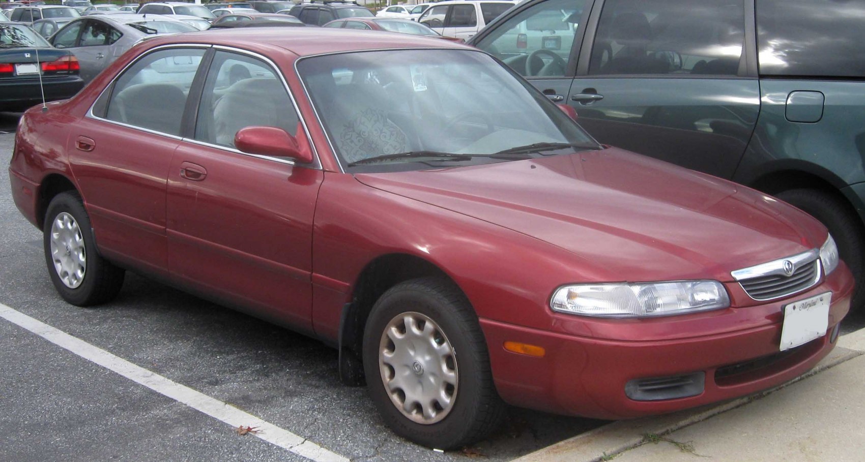 Front side view of red four-door sedan with alloy wheels.