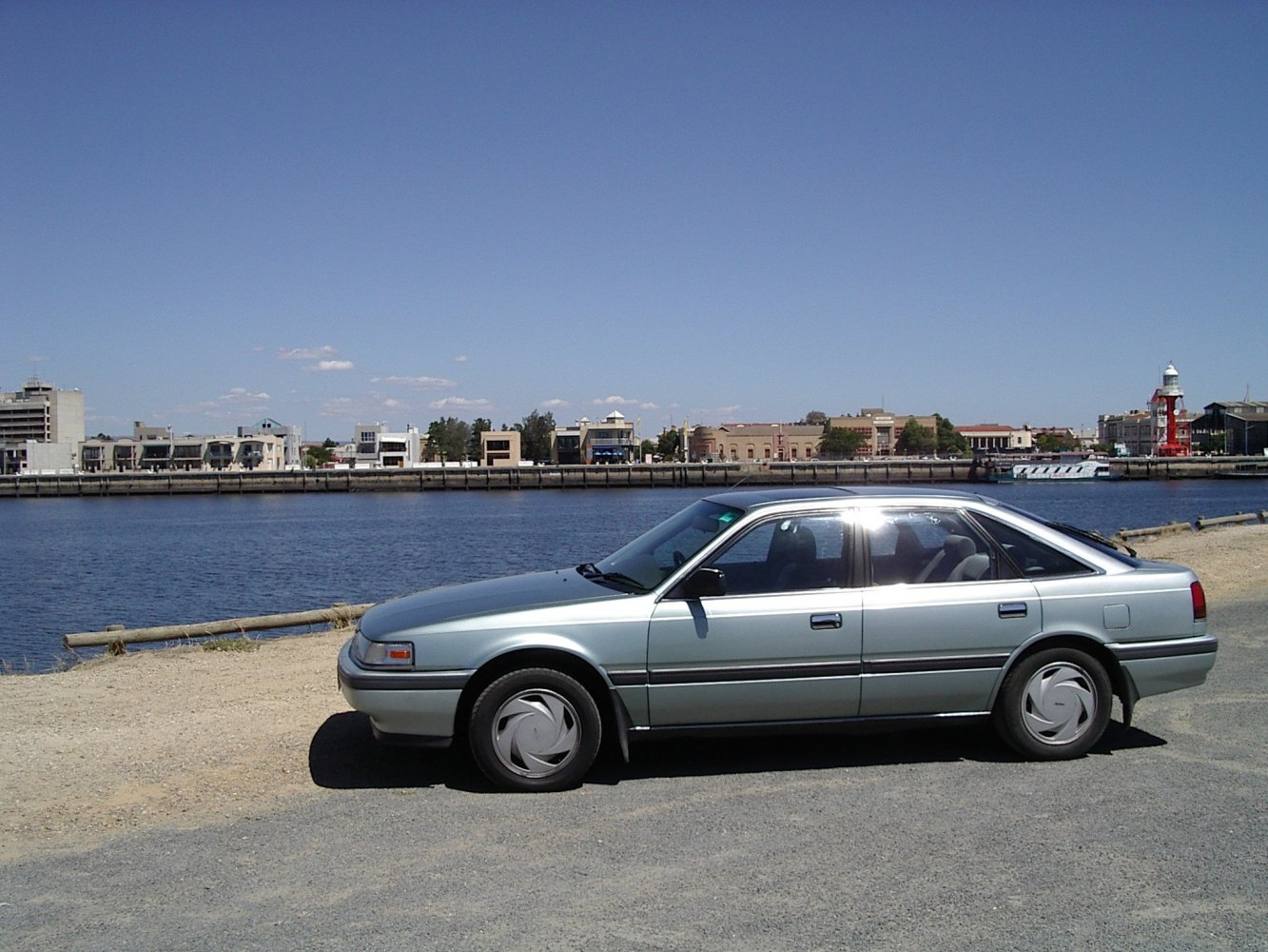 Side profile of a classic 1980s sedan with aerodynamic shape and detailed wheel covers