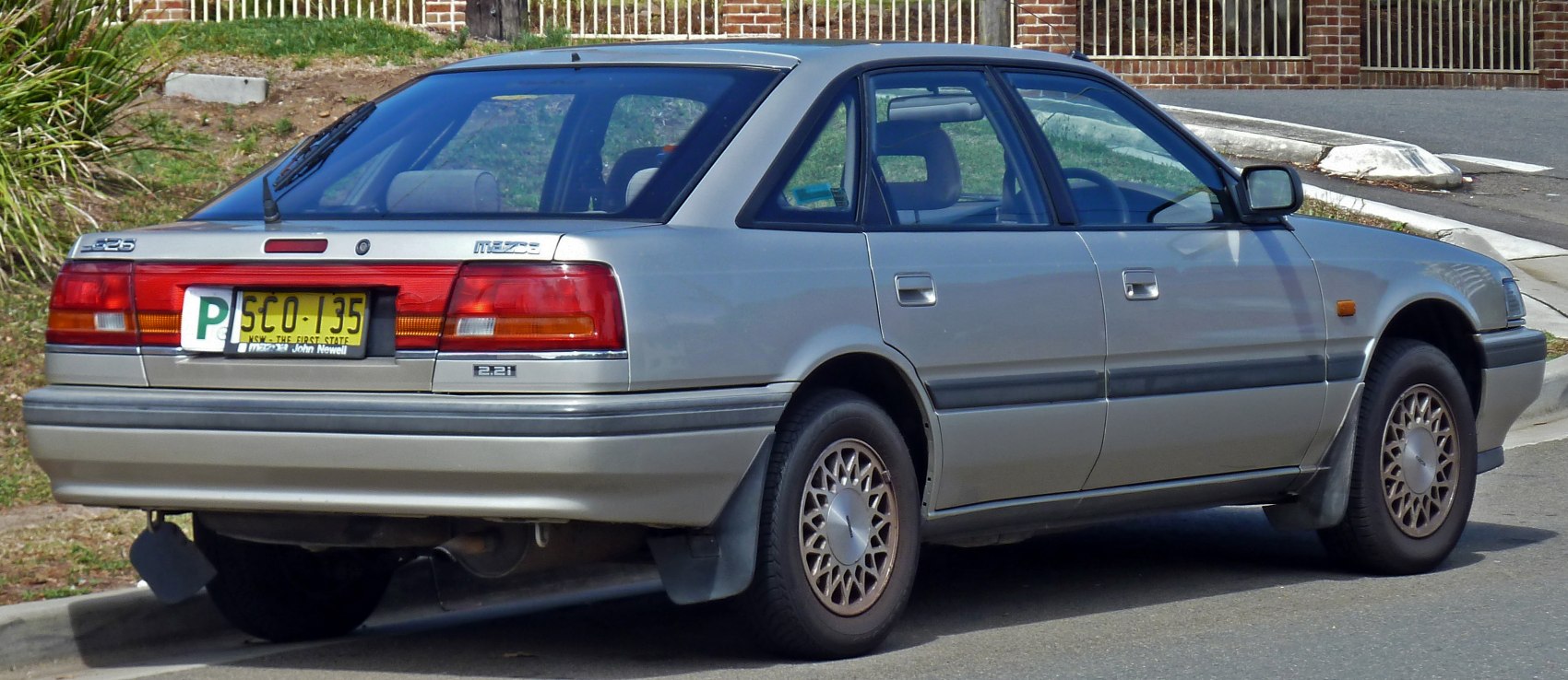 Rear side view of a vintage four-door sedan with alloy wheels and distinctive taillights.