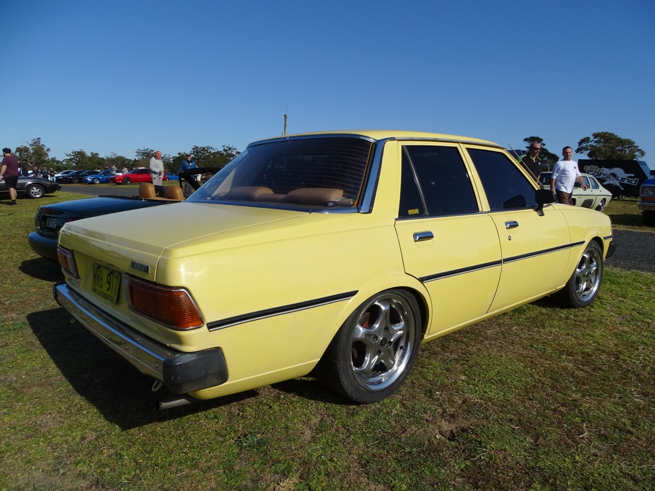 Vintage four-door sedan in yellow with custom chrome wheels.
