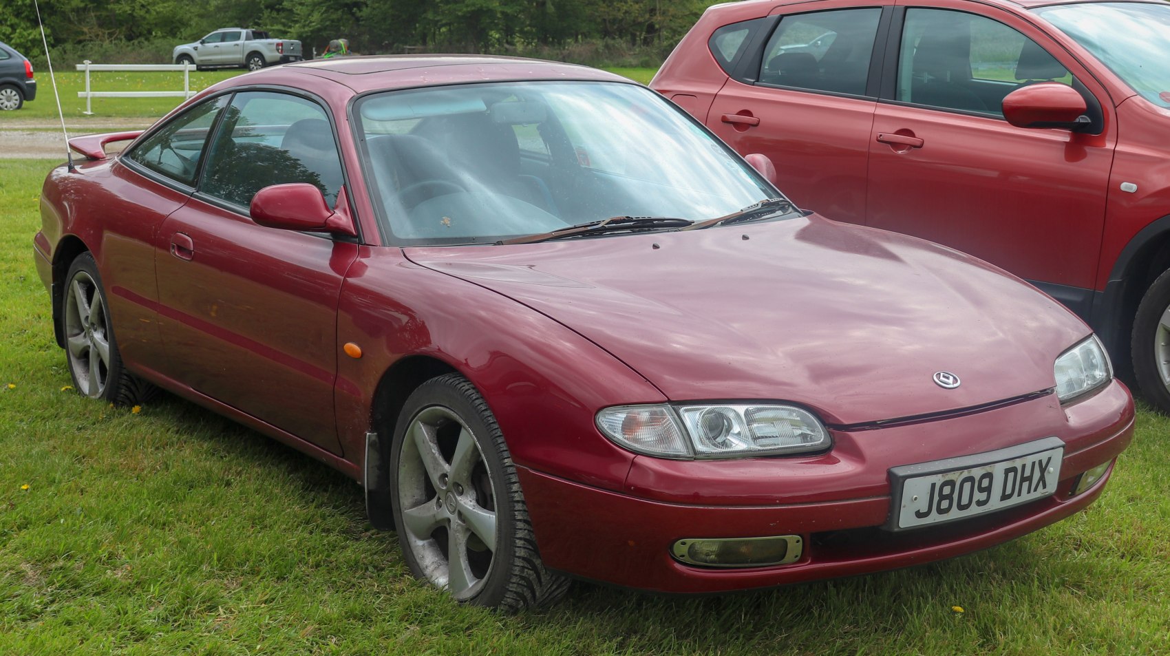 Red 1992 sports coupe with aerodynamic front side profile and alloy wheels