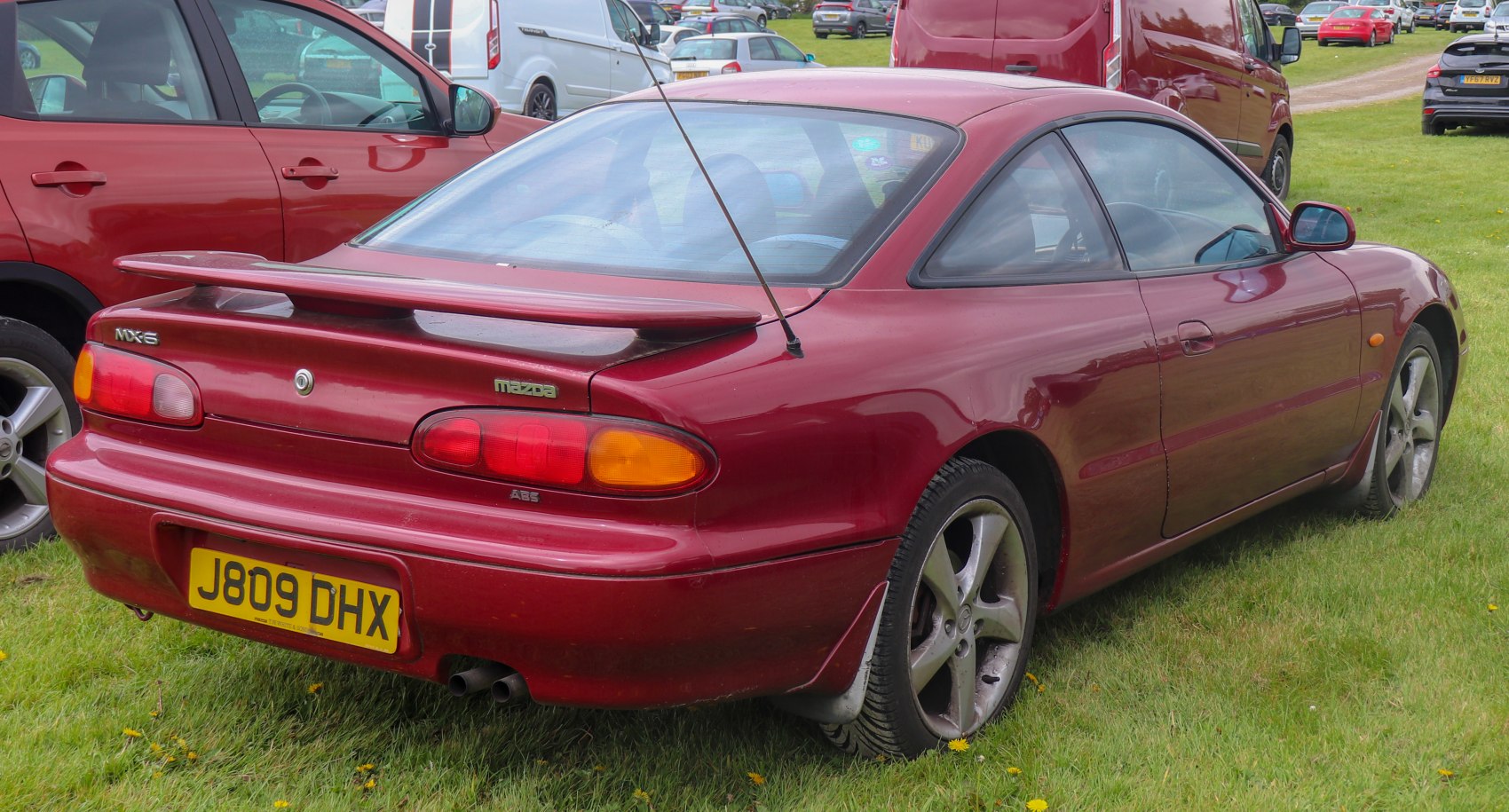 Rear and side view of red coupe with spoiler and rounded taillights