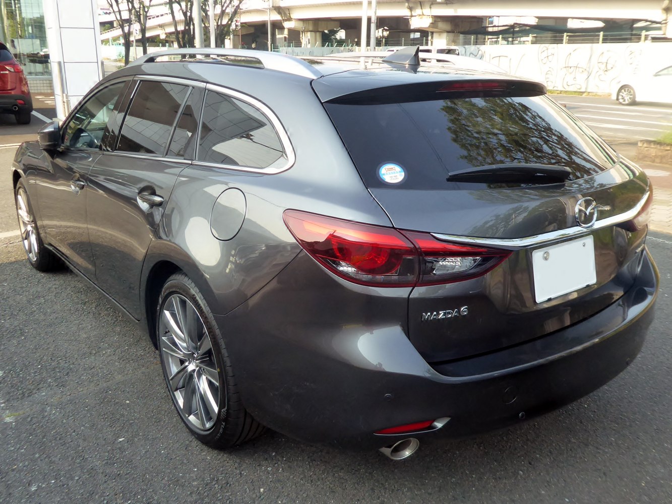 Rear and side view of a gray station wagon with tinted windows and alloy wheels