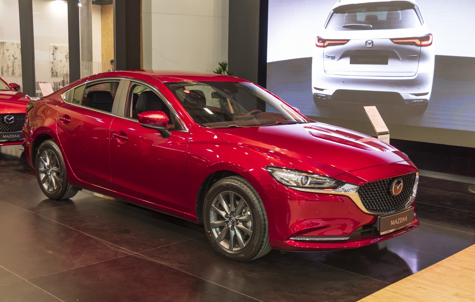 Red sedan with sharp LED headlights and prominent front grille