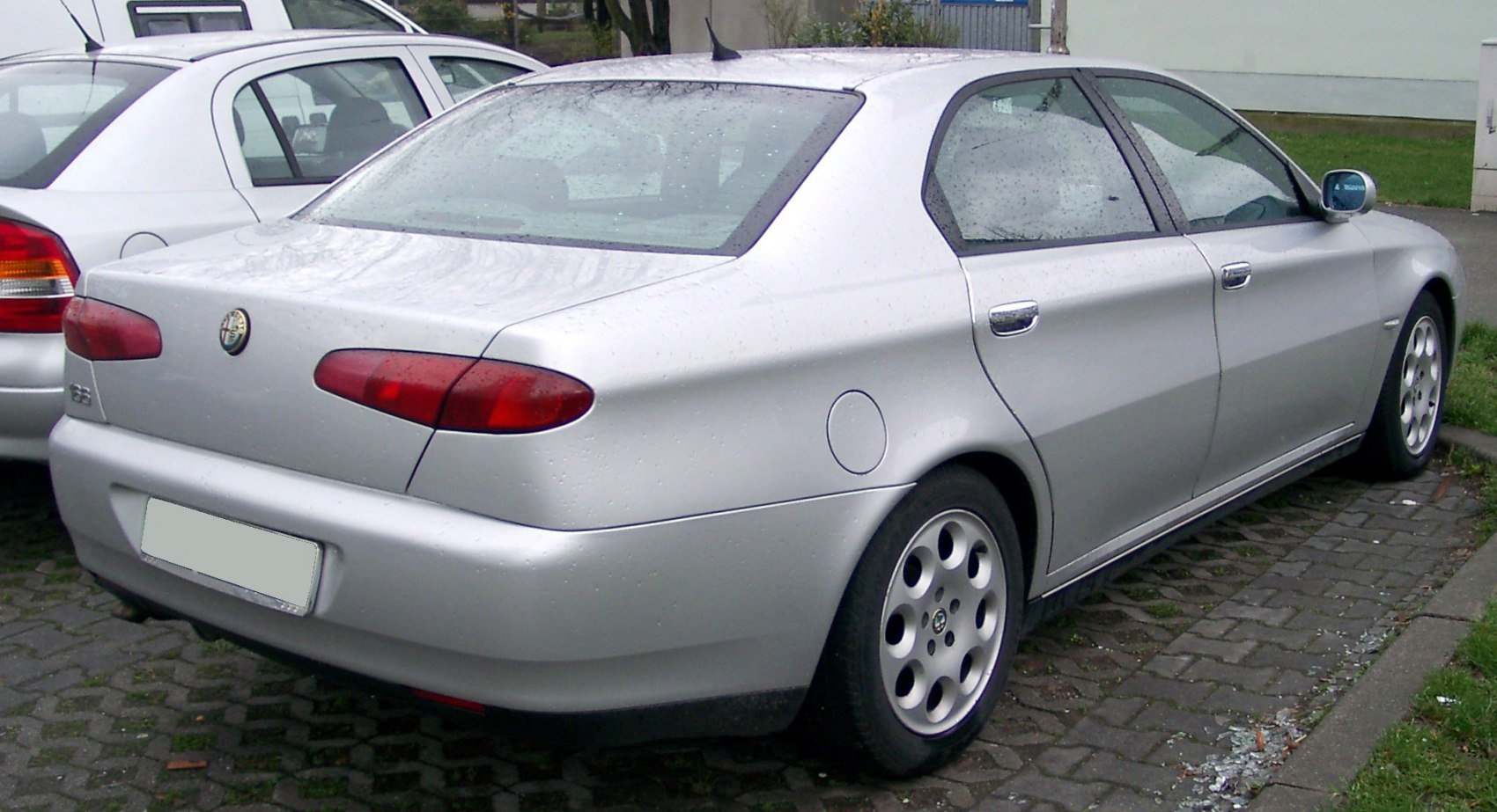 Silver sedan rear with oval taillights and multi-hole alloy wheels