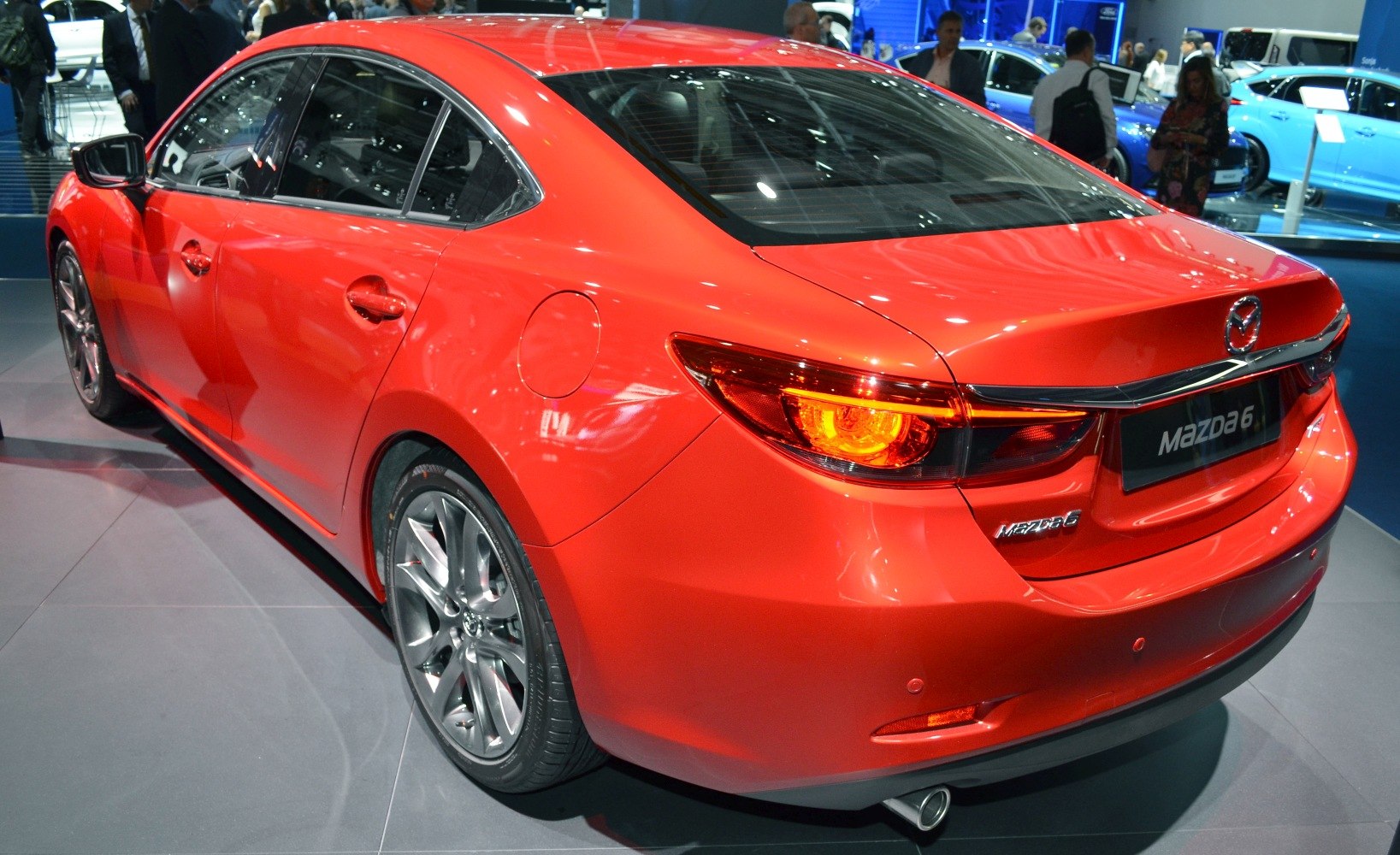Rear and side view of red sedan with glowing taillight and alloy wheel