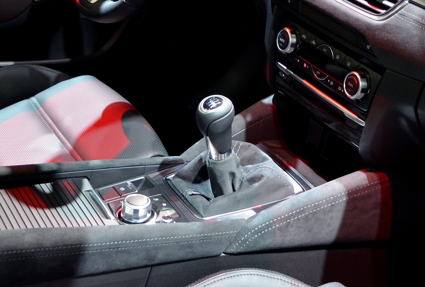 Manual gear shift lever with center console controls and textured upholstery