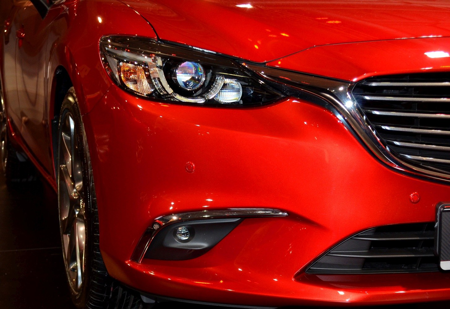 Front headlight, grill, and fog light close-up on red car