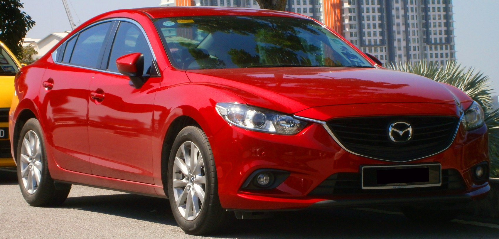 Red mid-size sedan with sleek headlights and alloy wheels from the front-side view.