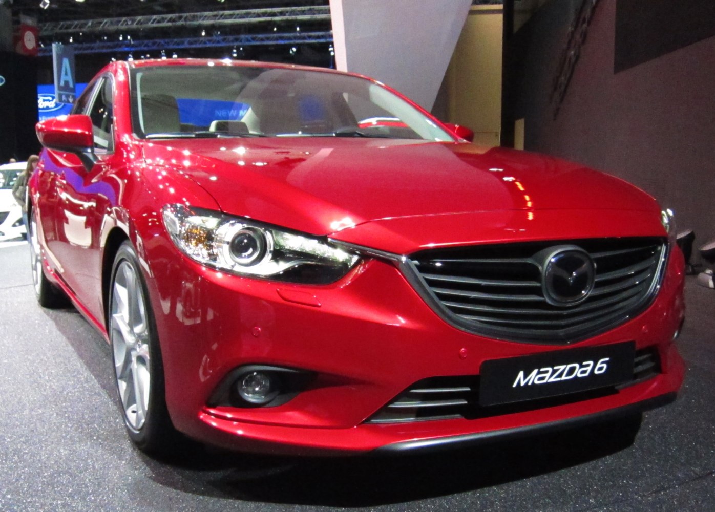 Close-up front view of sedan headlight and grille in red.