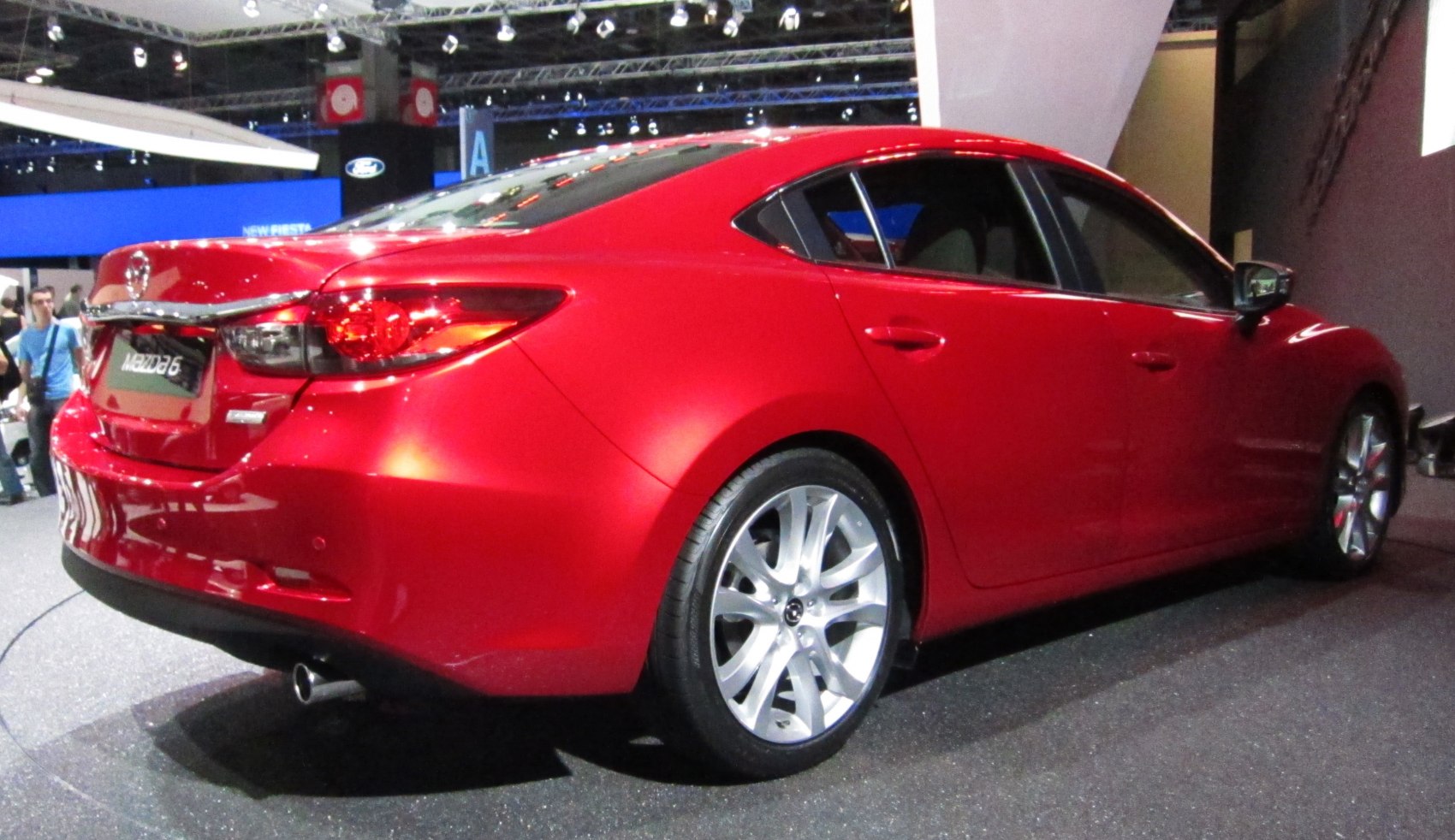 Rear and side profile of a red sedan with alloy wheels