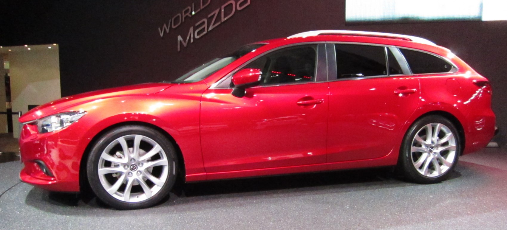 Red station wagon showing side view with alloy wheels.