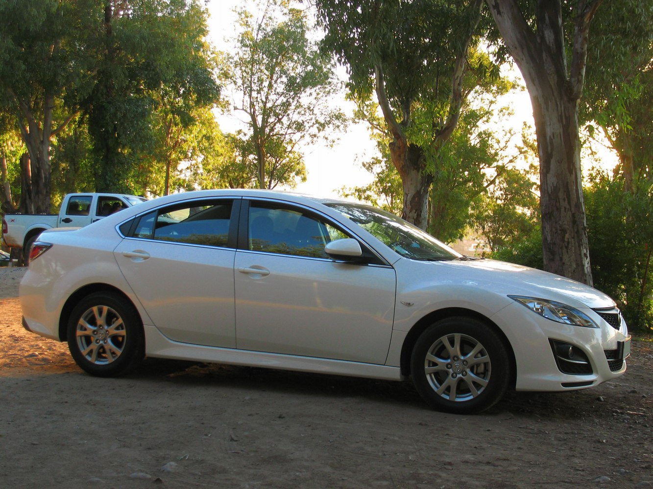 White four-door sedan with alloy wheels in outdoor setting