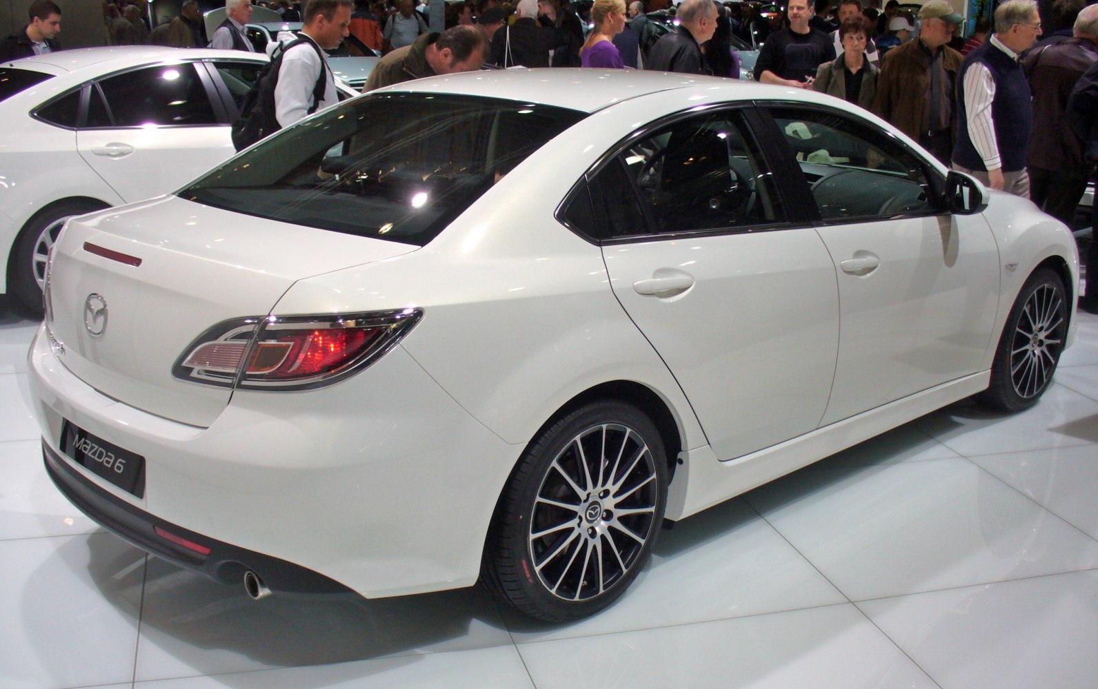 Rear side view of a white mid-size sedan with alloy wheels