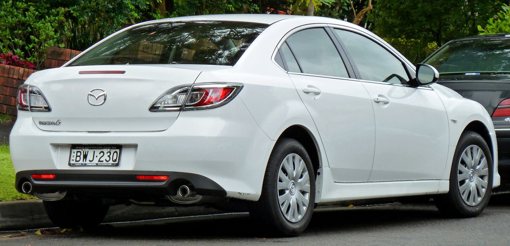 White mid-size sedan rear and side view with taillights and dual exhausts