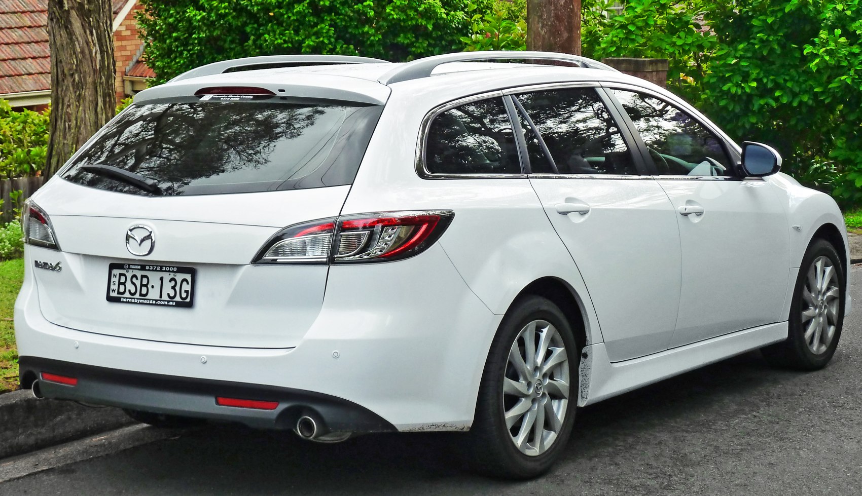 Rear side view of white station wagon with roof rails and dual exhaust