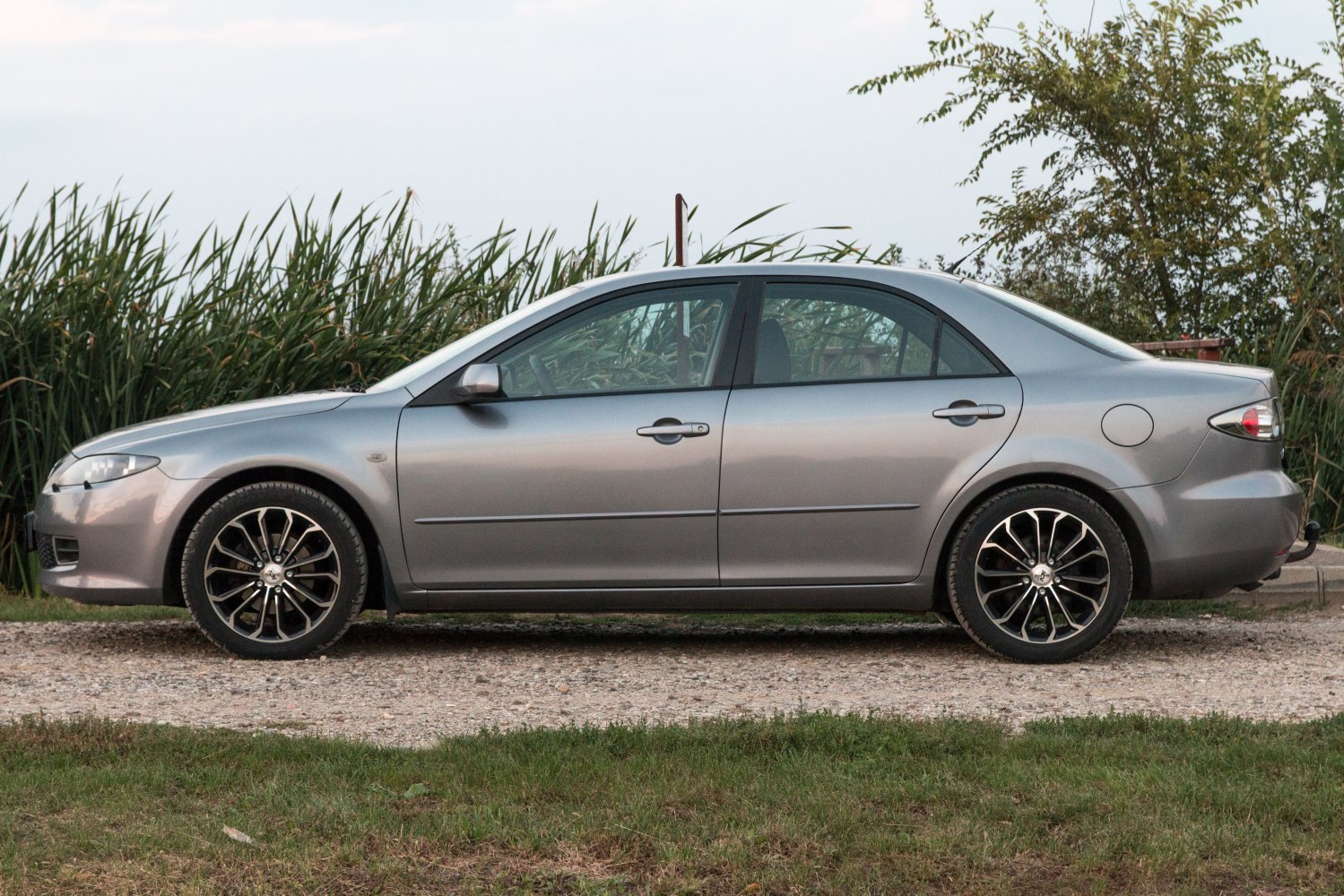 Side profile of a sedan with alloy wheels on gravel road