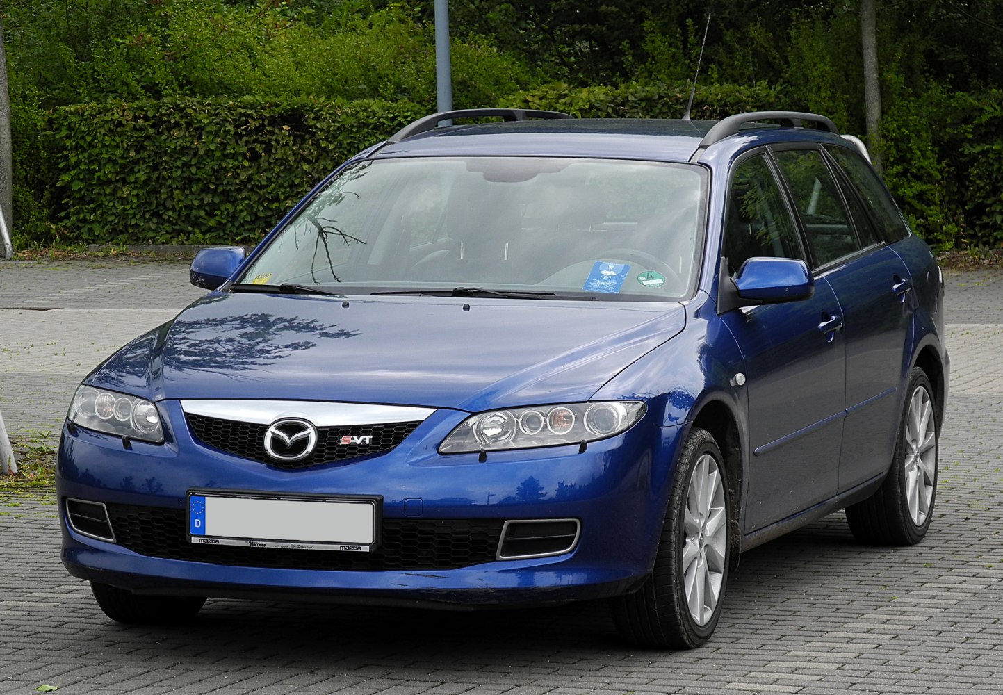Blue station wagon with roof rails, alloy wheels, and dual round headlights