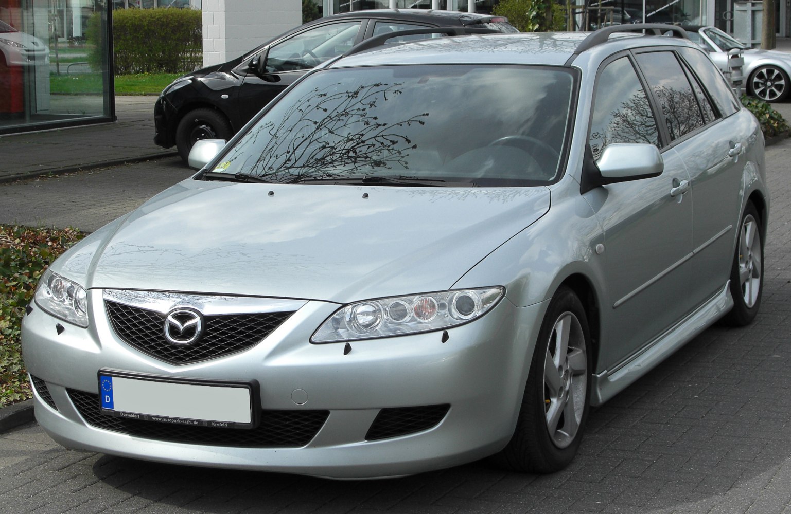 Front and side view of a silver station wagon with distinct headlights and roof rails