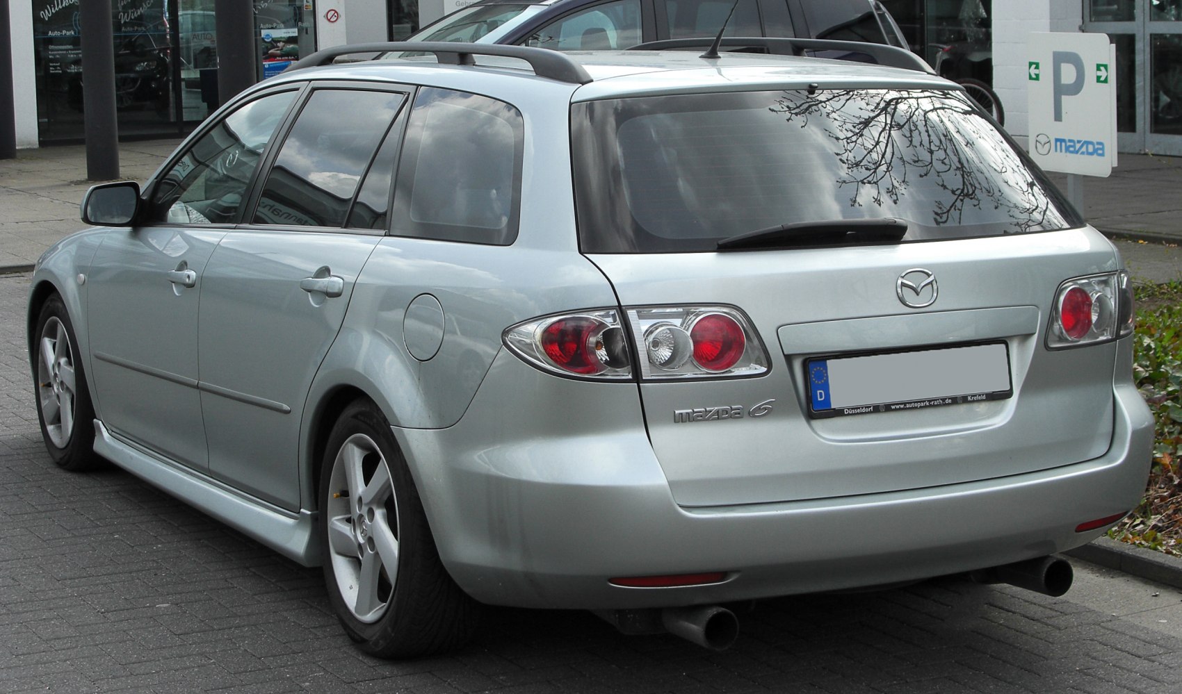 Rear side view of silver station wagon with unique taillights and roof rails