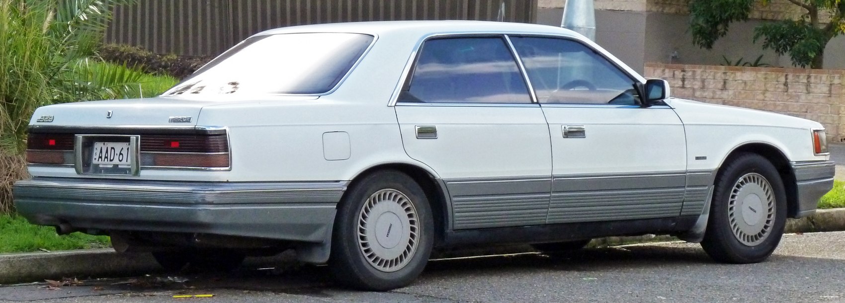 Rear and side profile of a classic sedan with horizontal tail lights and unique rims.