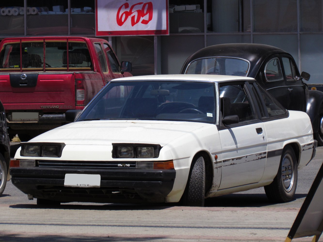 White coupe with pop-up headlights and streamlined two-door design.
