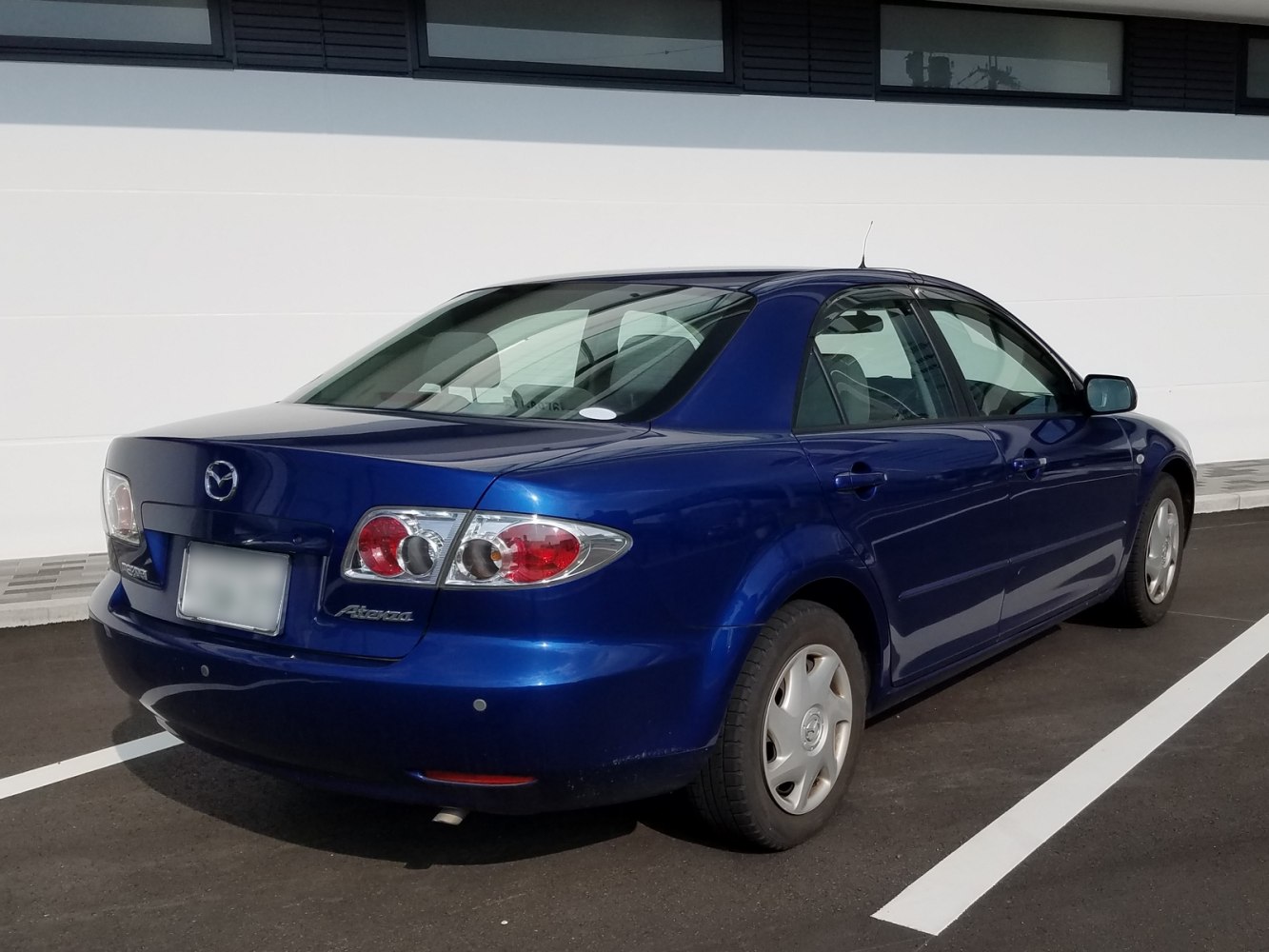 Rear and side view of blue sedan with distinctive tail lights