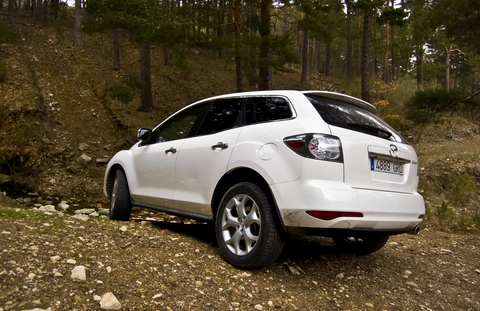 Rear side view of SUV on rugged terrain with alloy wheels and tinted windows