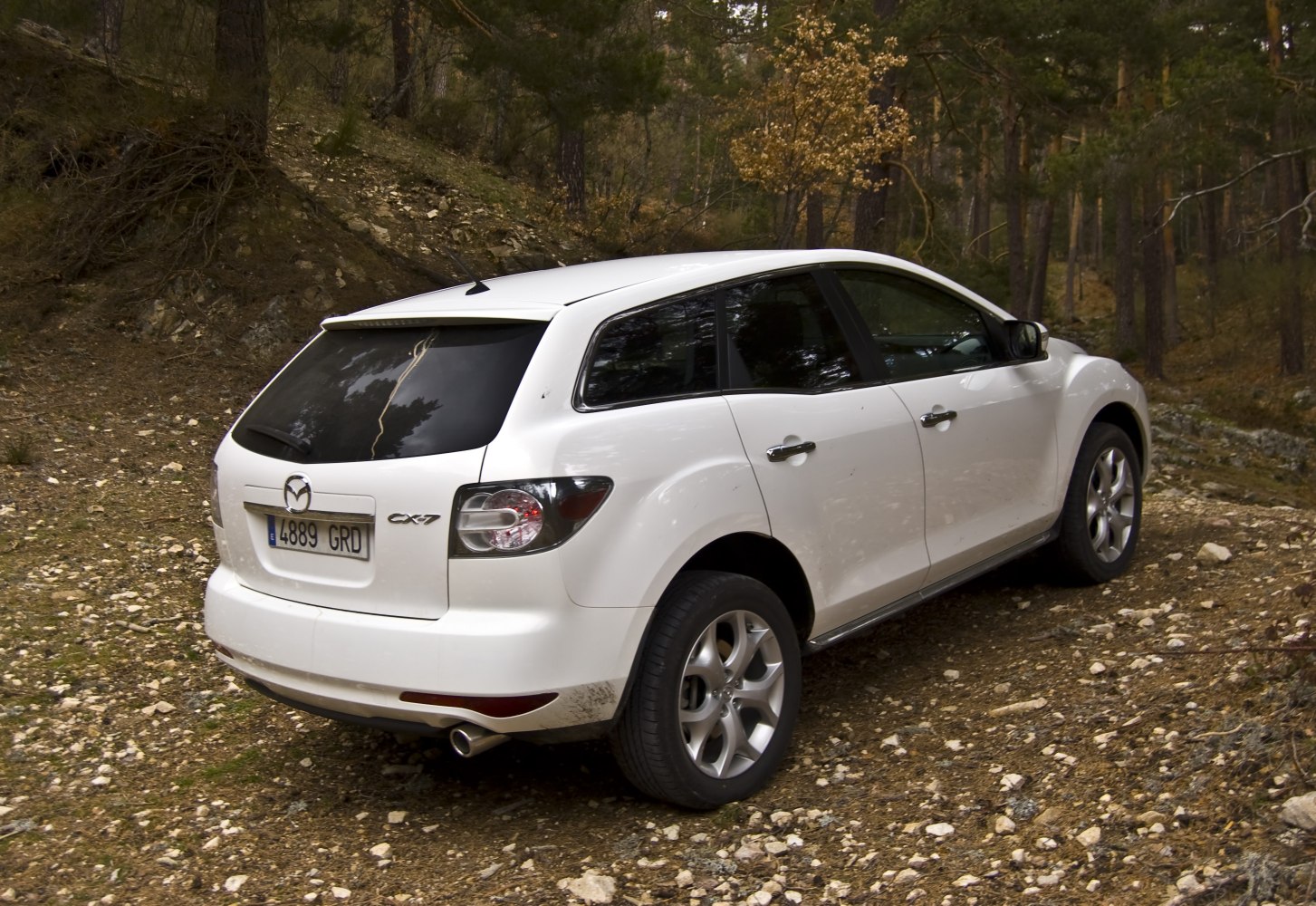 Rear side view of white SUV on rocky terrain