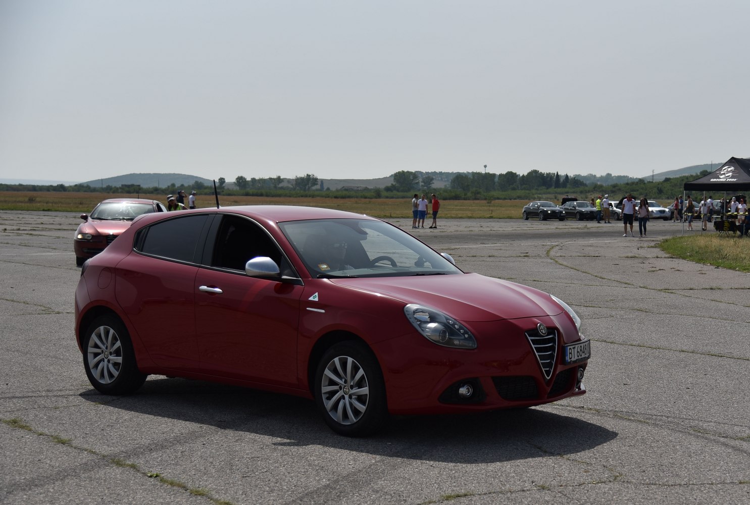 Red hatchback, front side view, outdoor pavement