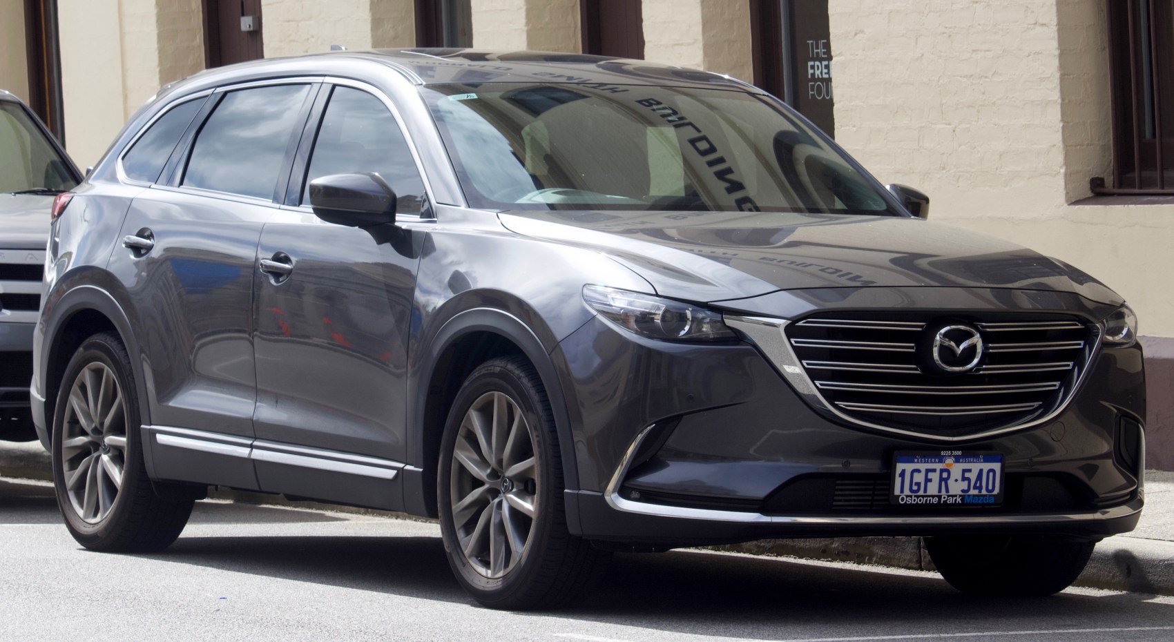 Front side view of SUV with sleek headlights and prominent grille