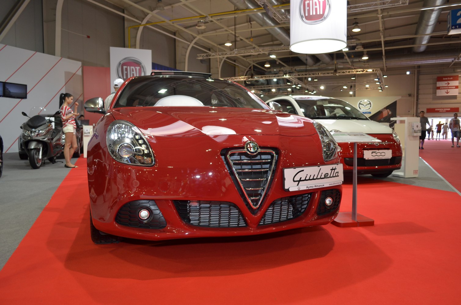 Close-up of a red sports sedan front with distinctive triangular grille and sleek headlights.